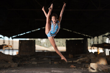 Fototapeta na wymiar Young girl performing rhythmic gymnastics exercises outdoors