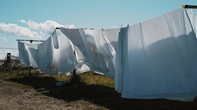 white bed sheets on a clothes line moving gently with the wind in a natural setting