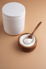 collagen powder in a wooden bowl on a brown background, side view, jar