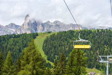 Yellow chairlift connecting valley floor to high peaks of Italian Alps. Sassongher Dolomite...