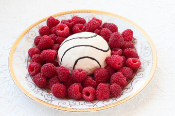 White plate with raspberries and sponge cake on a white background.