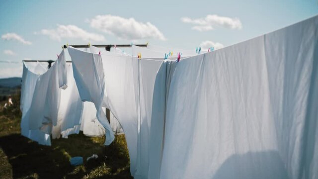 white bed sheets on a clothes line moving gently with the wind in a natural setting