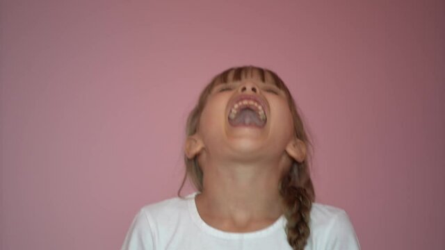 Child Shouting Loud on a pink background. Portrait of Shocked, Angry and Emotional Little Girl. Young Angry Girl Yelling Screaming Slow Motion. Upset Child Scream Loudly.