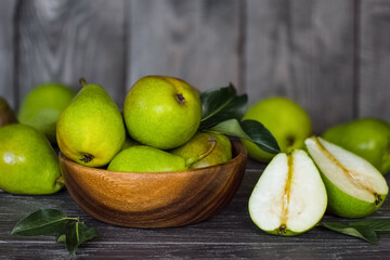 ripe pears in a wooden bowl on the table close-up. background with pears close-up. pears and green leaves on a wooden background.