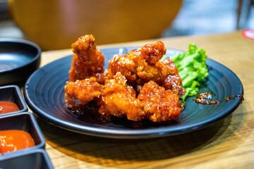 Eating Korean style spicy sauce deep fried chicken on plate with spoon and fork