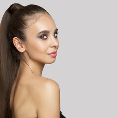 Fototapeta premium beautiful woman with makeup on a gray background. High ponytail and long hair. Copycpase