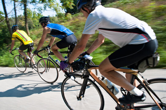 Three Avid Cyclists Zooming Down Country Road