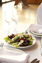 Table setting. Vegetable salad in a white plate on a light table