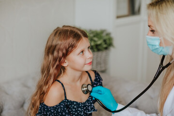 Doctor inspecting by stethoscope a girl in the grey room. Focus is at the girl.