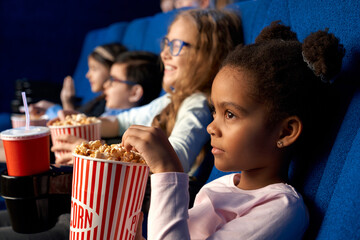 African girl watching cartoon with friends in cinema.
