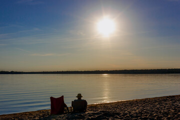 couple of sunset lovers sitting on the beach of Manitoulin island, admiring the view of Huron Lake, Canada