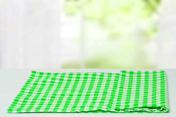Empty table product. Closeup of a empty green checkered tablecloth or napkin on a bright table over abstract blurred curtain background. Template for your food and product display montage.