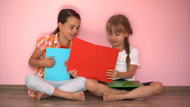 Adorable little girls study at home with books, girls playing together, drawing, doing homework at home. friends having fun learning
