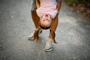 close-up of the face of little girl which her father hold upside down and swing her