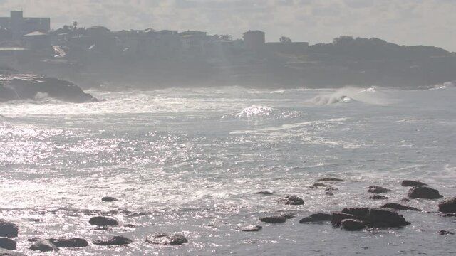 A wave crashes at a beach in Malibu california during a summer morning