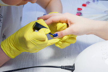 Applying a colors nail polish by a qualified master in a beauty salon.