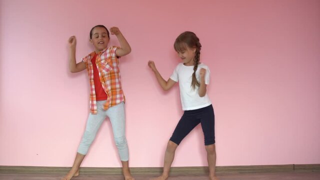little smiling girls, sisters, best friends hug on a pink background, children hug each other