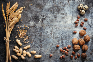 Gifts of autumn harvest. Golden ripe ears of wheat plant, grains, peanuts, walnuts, hazelnuts and quails eggs on rustic metal background. Top view and copy space for your advertising text message.