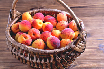 Natural ripe apricots in a wicker basket on a natural wooden background