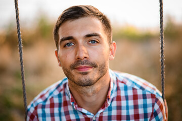 portrait of man with in plaid shirt in the park on blurred background.