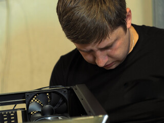 a young man builds a personal computer. workshop. repair. computer case.