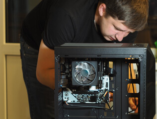 a young man builds a personal computer. workshop. repair. computer case.