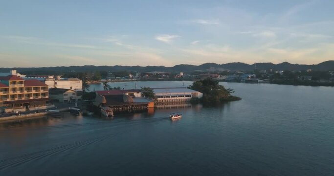 Aerial drone shot of a boat driving through the lake during sunset in Peten, Guatemala
