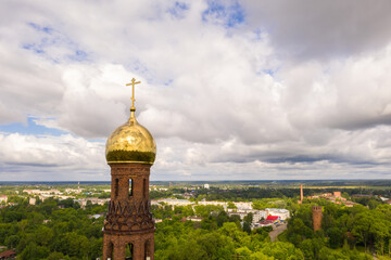 The upper part of the bell tower with a golden dome and a cross of the Church of the Resurrection of Christ in Vichuga, Ivanovo region, Russia.