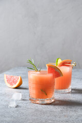 Two honey rosemary grapefruit sodas on light grey. Vertical format.
