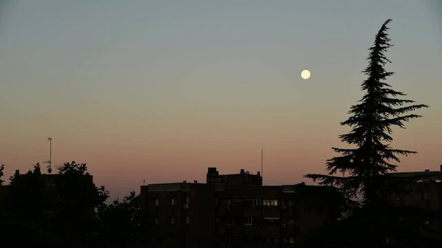 Time-lapse of moon moving over city at sunrise