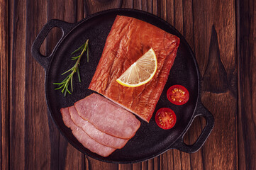 Sliced smoked pork loin on an iron plate isolated - Top view