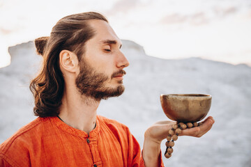 Close-up of hands with rosary playing on singing bowls. Relaxation and meditation. Alternative...