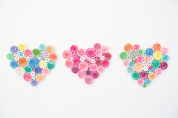 Hearts from colored paper ribbons on a white background in the style of quilling.