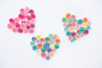 Hearts from colored paper ribbons on a white background in the style of quilling.