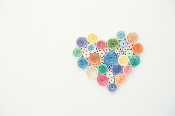 Heart from colored paper ribbons on a white background in the style of quilling.