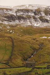 Snow topped mountain in North Yorkshire with farm building in the foreground 