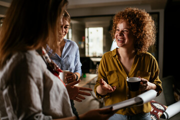 Happy businesswomen talking and laughing in office. Beautiful women drinking coffee in the office.