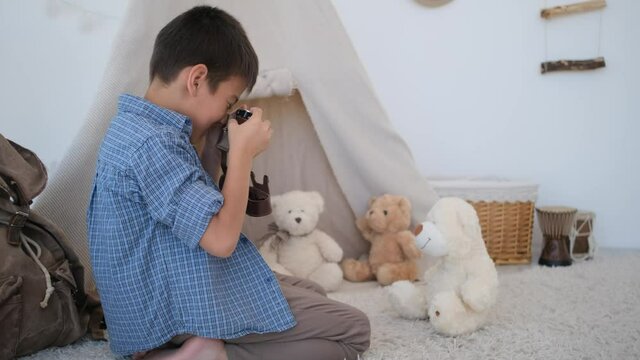 Little boy photographer shooting teddy bear in light room