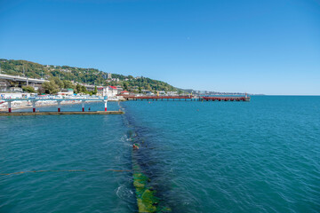 View of the bay, beach and houses and the watershed from the water, a man swims in the bright transparent water on a cloudless sunny day