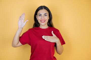 Young beautiful woman over isolated yellow background doing ok sign with fingers and smiling, excellent symbol.