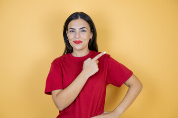 Young beautiful woman over isolated yellow background smiling pointing with hand and finger to the side.