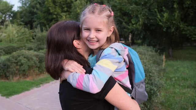 Little girl hugging mother in park after school