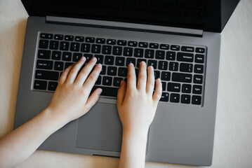 Hands of a child close-up on the laptop keyboard. Distance learning. Stay at home