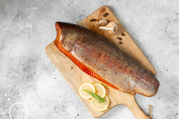Smoked fish trout. Whole Smoked trout on the serving Board. Smoked trout lay on the light gray kitchen table. Smoked fish close-up