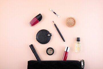 Black cosmetic bag with makeup. Eyeshadow, lip gloss, brushes, perfume, nail polish. Flat lay.