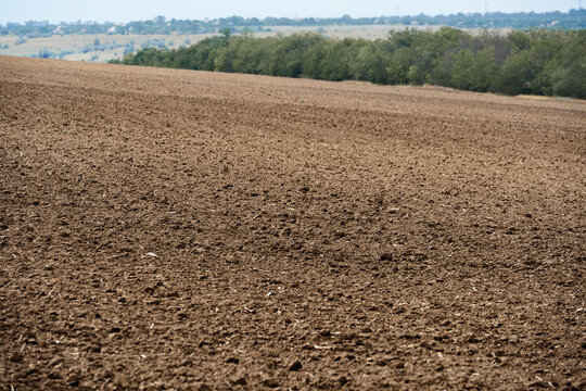 plowed field and blue sky, soil and clouds of a bright sunny day - concept of agriculture