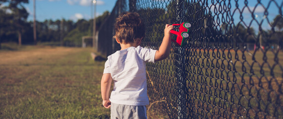 boy at a baseball park practice playing with his toy car in the fence stock photo royalty free 