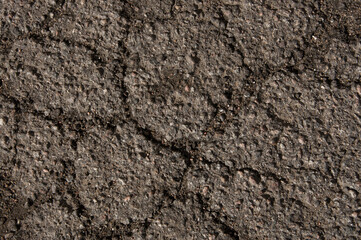 Texture of an old asphalt road with cracks and water stains close-up.