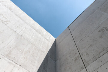 Vértice de dos muros de concreto aparente con fondo de cielo azul. Sombra y luz de día. Captura horizontal. 