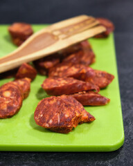 chorizo on a green board with a wooden spatula